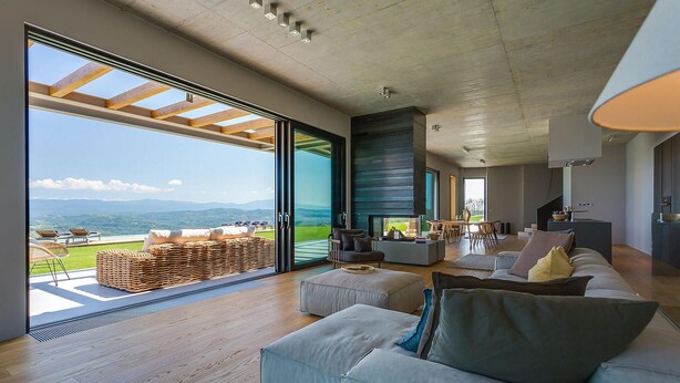 A spacious living room with a large sliding glass door leading to a balcony with a view of the mountains. - Luxurious home in Pazin (Pazin)