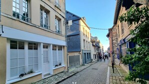 A cobblestone street lined with historic buildings, featuring a mix of architectural styles and a clear sky.