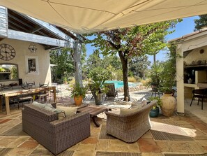 Un patio con mobiliario de mimbre, una piscina y una pérgola que ofrece sombra.