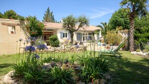 A house with a stone garden, a pool, and a patio with a chair.