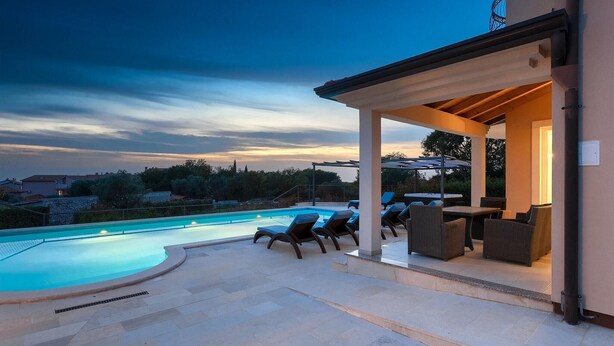 A swimming pool with lounge chairs and a covered patio area.