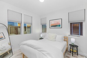 A bedroom with a bed, bedside tables, a mirror, and a window with blinds. - Calm Urban Abode steps to Volunteer Park (Seattle)