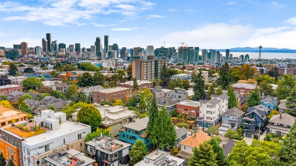 A cityscape with a mix of residential and commercial buildings, including a prominent tower and a bridge in the distance. - Calm Urban Abode steps to Volunteer Park (Seattle)
