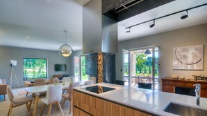 A modern kitchen with a central island, wooden cabinets, and a large window. - Gorgeous home in Sivati (Sivati)
