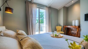 A bedroom with a large bed, a bedside table with a tray of items, a chair, and a wooden cabinet. - Gorgeous home in Sivati (Sivati)