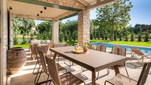 An outdoor patio with a pool, wicker furniture, and stone pillars. - Gorgeous home in Sivati (Sivati)