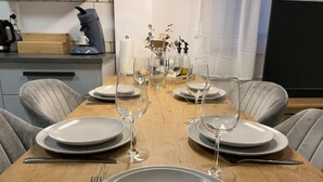 A dining table set with plates, glasses, and cutlery, with a coffee maker and decorative items on the counter. - Modern furnished holiday apartment with two bedrooms and a workspace (Euskirchen)
