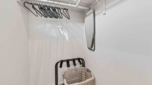Un espace dédié à la lessive, équipé d’un étendoir, d’un panier et d’une fenêtre située en hauteur.