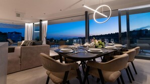 Ein moderner Essbereich mit Panoramablick, einem runden Tisch für vier Personen und einer gemütlichen Sitzecke mit einer Couch.