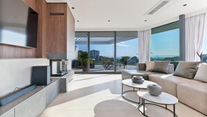 Ein modernes Wohnzimmer mit Flachbildfernseher, Kamin, Sofa und Balkon mit Blick auf die Stadt.