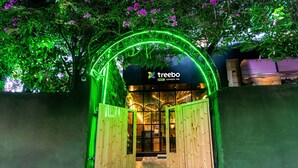 Entrada de uma casa na árvore com um arco de néon e uma placa indicando Treebo Express Inn.