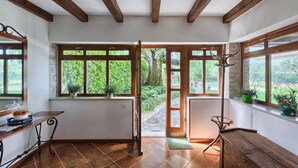 Una habitación con ventanas amplias, vigas de madera, un banco y plantas en macetas.