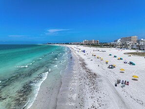 A beach with clear turquoise water, white sand, and several umbrellas.