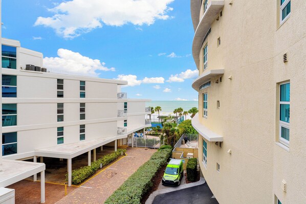 A modern hotel with a pool area, a covered walkway, and a view of the beach.
