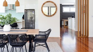 Una cocina moderna con armarios blancos, un refrigerador de acero inoxidable y una mesa de comedor de madera con sillas negras.