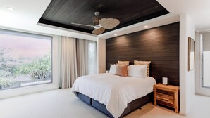 Un dormitorio moderno con una cama grande, un cabecero de madera, una mesita de noche y un ventilador de techo.