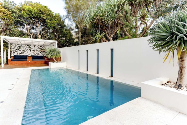 Relax by the pool surrounded by lush greenery and a minimalist design.