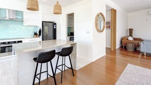 Una cocina moderna con una isla central, taburetes de bar e iluminación colgante.