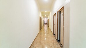 A long, narrow hallway with a shiny marble floor and white walls. - Itsy Hotels Mansi (Nashik)
