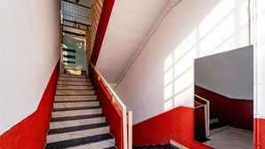 A staircase with red and white walls, a marble floor, and a metal railing. - Itsy Hotels Mansi (Nashik)