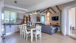 A modern kitchen with white cabinets, a dining table with white chairs, a grey sofa, and a TV mounted on the wall. - Amazing home in Zminj with sauna (Zminj)