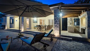 An outdoor patio area with a dining table, chairs, a large umbrella, and lounge chairs. - Amazing home in Zminj with sauna (Zminj)