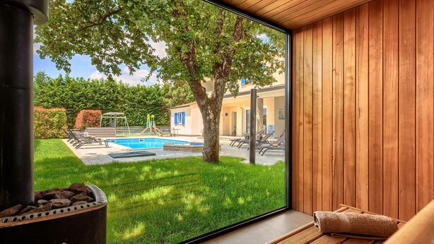 A modern room with a large window overlooking a swimming pool, a wooden deck, and a garden. - Amazing home in Zminj with sauna (Zminj)