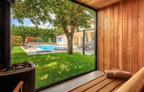 A modern room with a large window overlooking a swimming pool, a wooden deck, and a garden. - Amazing home in Zminj with sauna (Zminj)