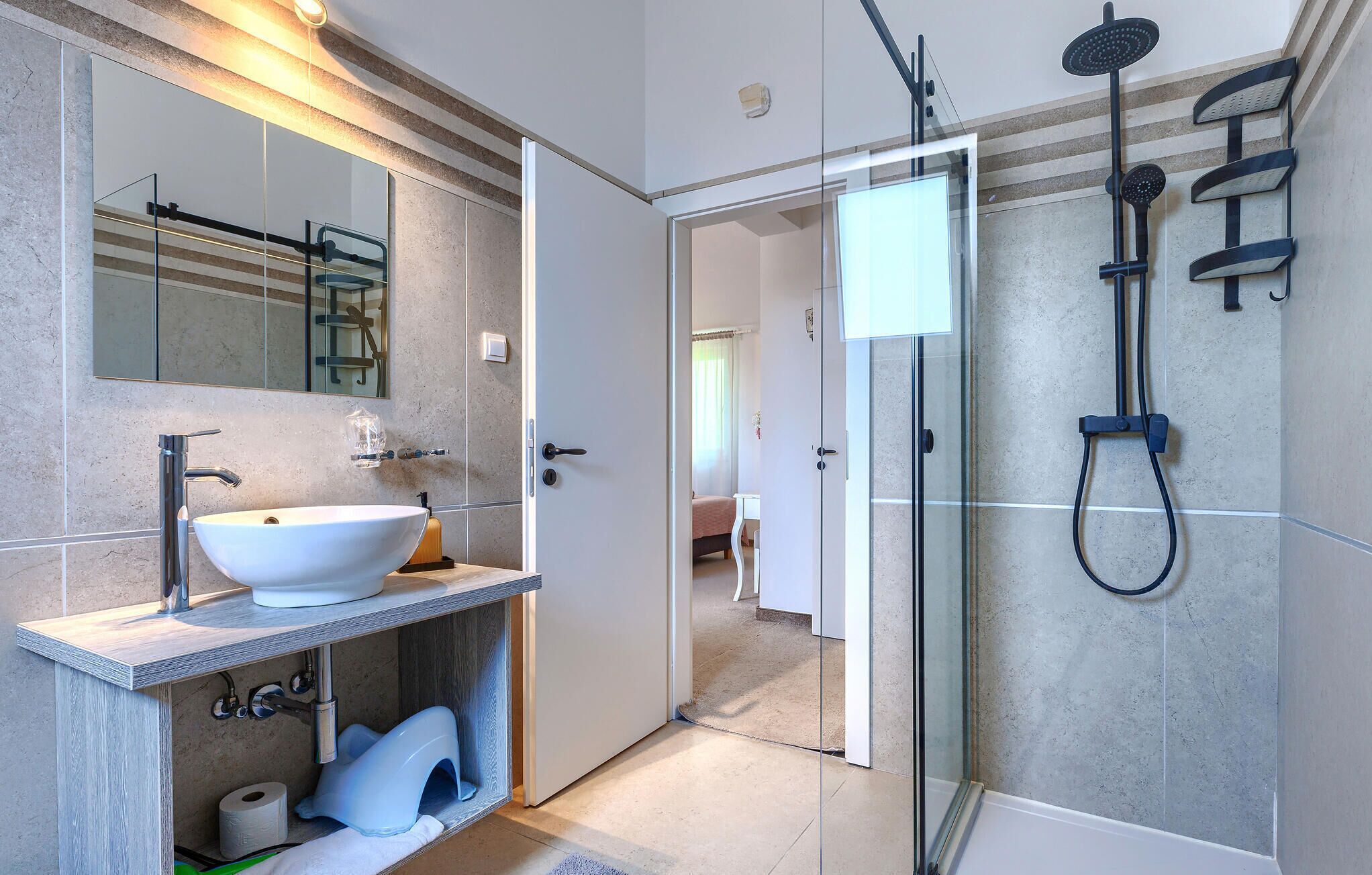 A modern bathroom with a large sink, mirror, and shower.