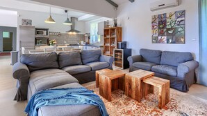 A modern living room with grey sofas, a wooden coffee table, and a colorful abstract painting on the wall. - Amazing home in Zminj with sauna (Zminj)