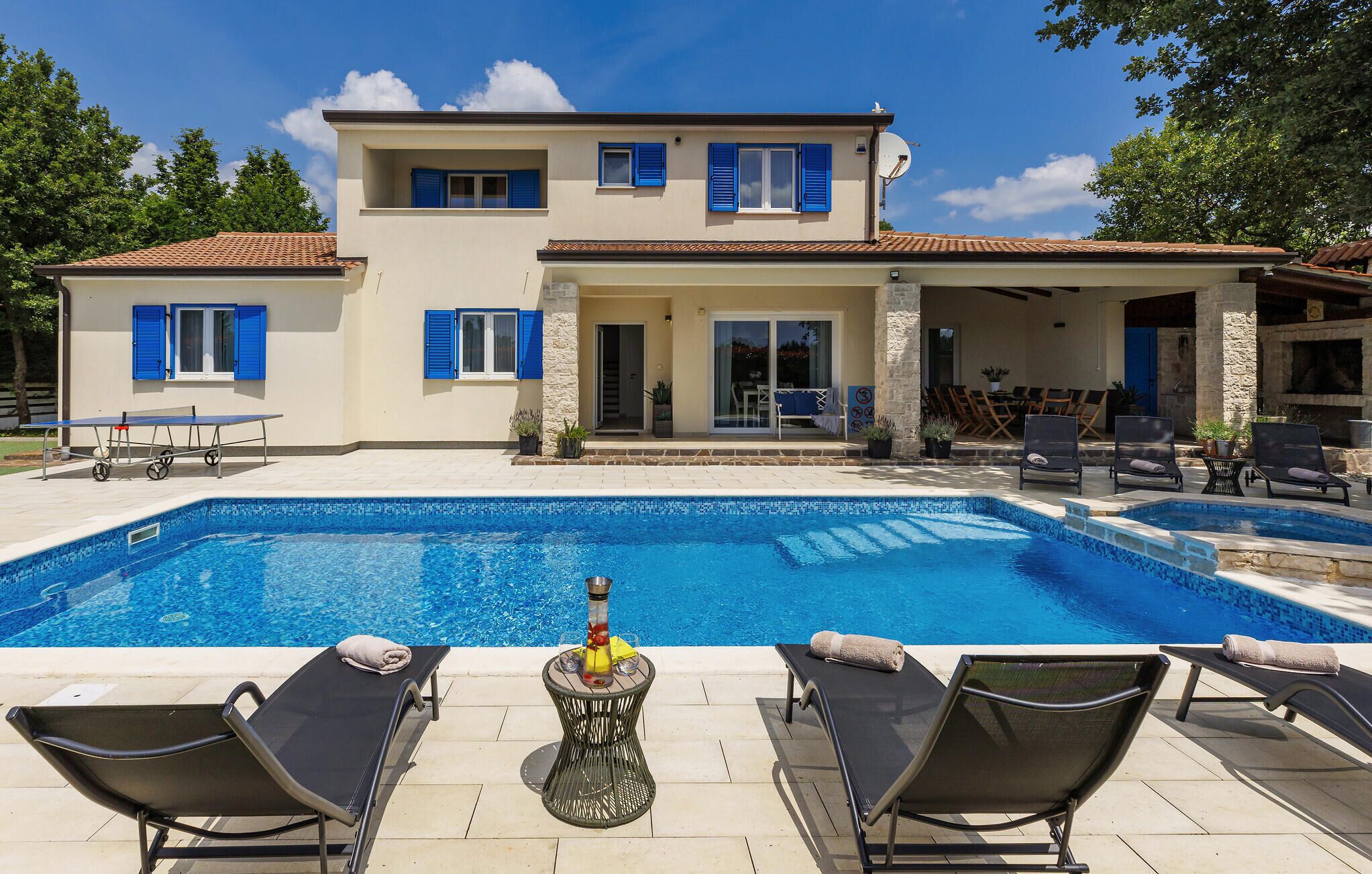 A two-story house with a swimming pool, outdoor seating, and a covered patio area.