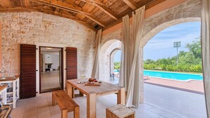 A covered outdoor area with a pool, wooden furniture, and stone walls. - Pet friendly home in Tinjan (Tinjan)