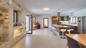 A modern kitchen with a stone wall, wooden cabinets, and a central island with bar stools. - Pet friendly home in Tinjan (Tinjan)