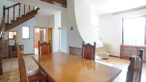 Un comedor espacioso con una gran mesa de madera, una escalera de madera y vistas al exterior.