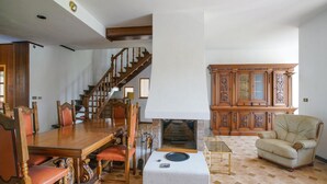 Una sala de estar amplia con una mesa de comedor de madera, una chimenea, una escalera y un mueble grande.