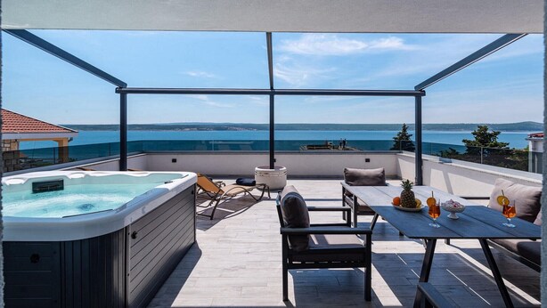 Eine Dachterrasse mit Whirlpool, Sitzgelegenheit und einem Tisch mit Getränken.