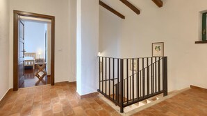 Una scala con ringhiera in metallo nero, travi in legno a soffitto e un quadro appeso al muro.