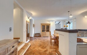 Enjoy meals and relaxation in this open-plan living space with a kitchen area, dining table, and comfortable seating.