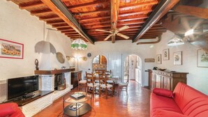 A spacious living room with a fireplace, a dining area, and a red sofa. - 2 bedroom nice home in Follonica (Follonica)