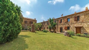 A courtyard with stone buildings, a well-maintained lawn, and a large evergreen tree. - 2 bedroom nice home in Follonica (Follonica)
