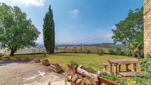 A patio area with a stone table, potted plants, and a view of vineyards in the distance. - 2 bedroom nice home in Follonica (Follonica)