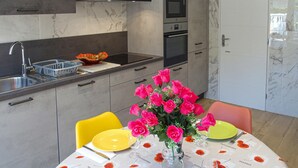 A modern kitchen with a marble backsplash, stainless steel appliances, and a dining area with a table set for two. - Nice home in Pierre-Châtel with WiFi (Pierre-Châtel)