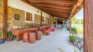 Un espacio al aire libre con techo, paredes de piedra, bancos de madera y una chimenea de ladrillo.