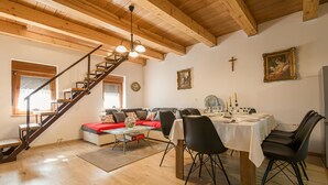 Un comedor con una escalera de madera, un sofá y una mesa dispuesta para comer.