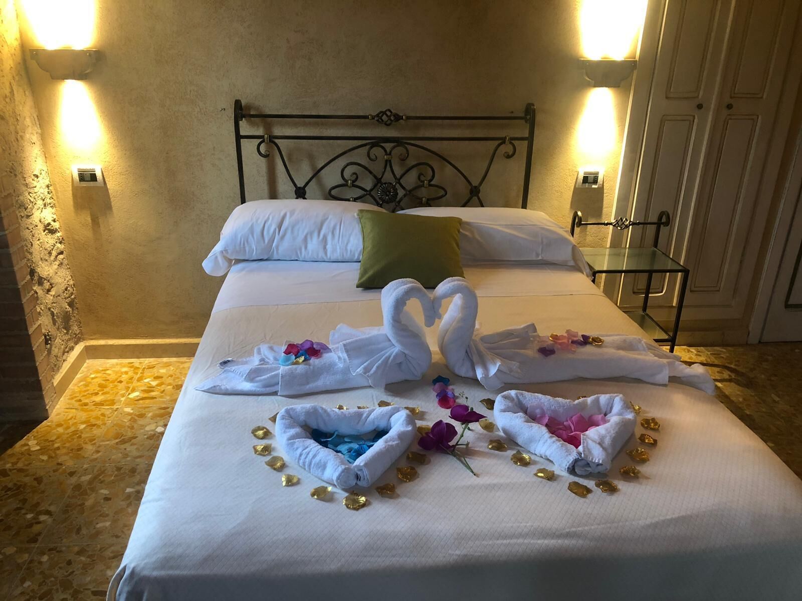 Un lit bien fait, avec du linge de lit blanc, un coussin vert et des serviettes décoratives en forme de cygne.