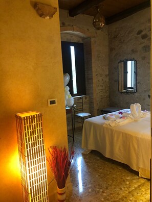 A room with a bed, a chair, a mirror, and a vase with red flowers. - Agriturismo limpero romano  (Gerace)