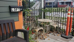 A residential area with a green house, a black bench, a wrought iron fence, and a small table with chairs. - Beautiful 1 Bedroom Loft with big jetted tub and shower also on-site parking ! (Indianapolis)
