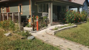 A residential house with a front porch, a small garden with flowers, and a paved pathway leading to the entrance. - Beautiful 1 Bedroom Loft with big jetted tub and shower also on-site parking ! (Indianapolis)