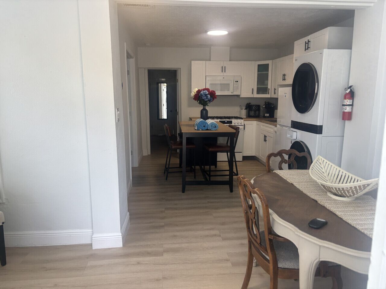 A kitchen with white cabinets, a microwave, a stove, and a washing machine.