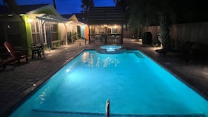 Une piscine à l’eau claire, entourée d’un patio aménagé avec des espaces de détente en plein air et un bar.